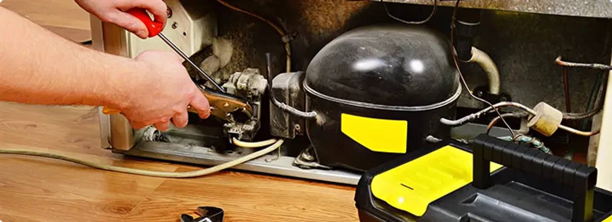 Refrigerator repair technician fixing the compressor and wiring in Buffalo, NY